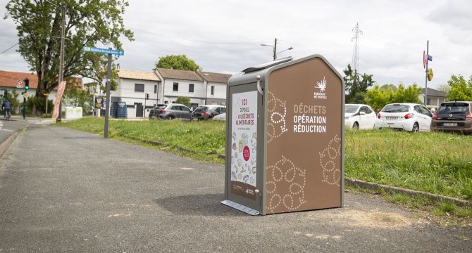 vue d'une nouvelle borne à déchets alimentaires sur un trottoir avec un parking en arriere plan